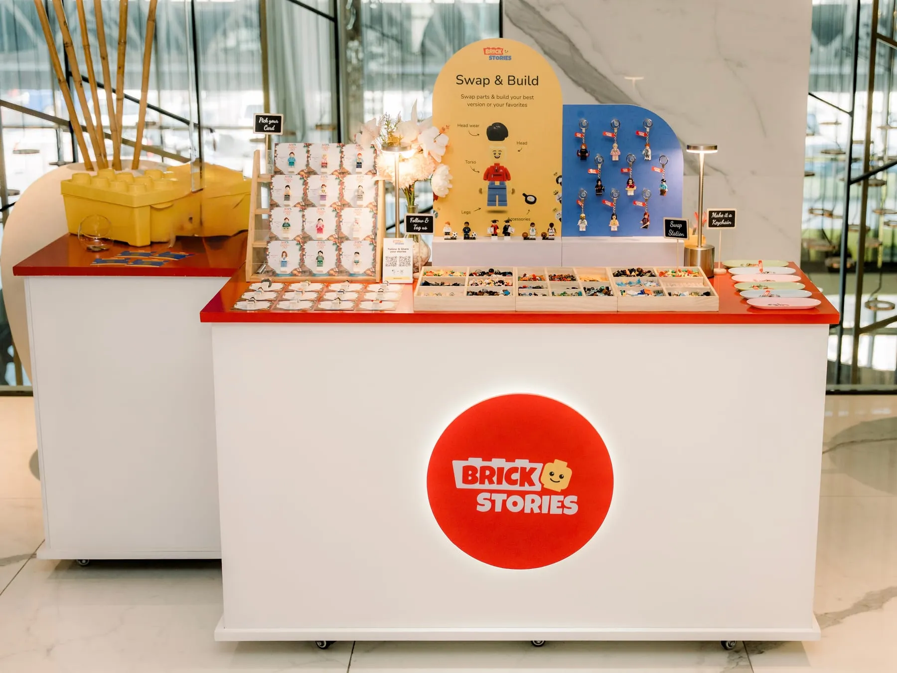 The Brick Stories booth set up at a venue in Dubai, with its Swap & Build station, keychain wall and figure display