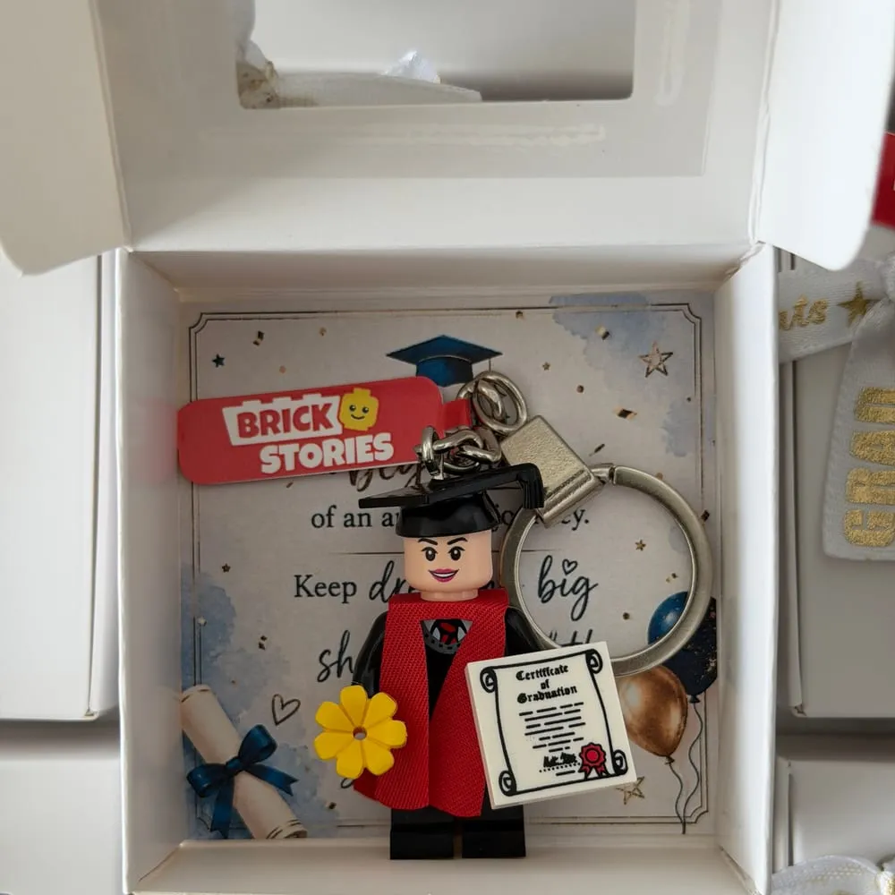 A graduate mini figure keychain in a gift box with a graduation card
