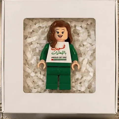 A mini figure in green wearing a Proud of UAE torso, boxed and ready to give
